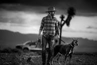 Black and white photo of man with hat and dog in Guanajuato's dramatic landscape.